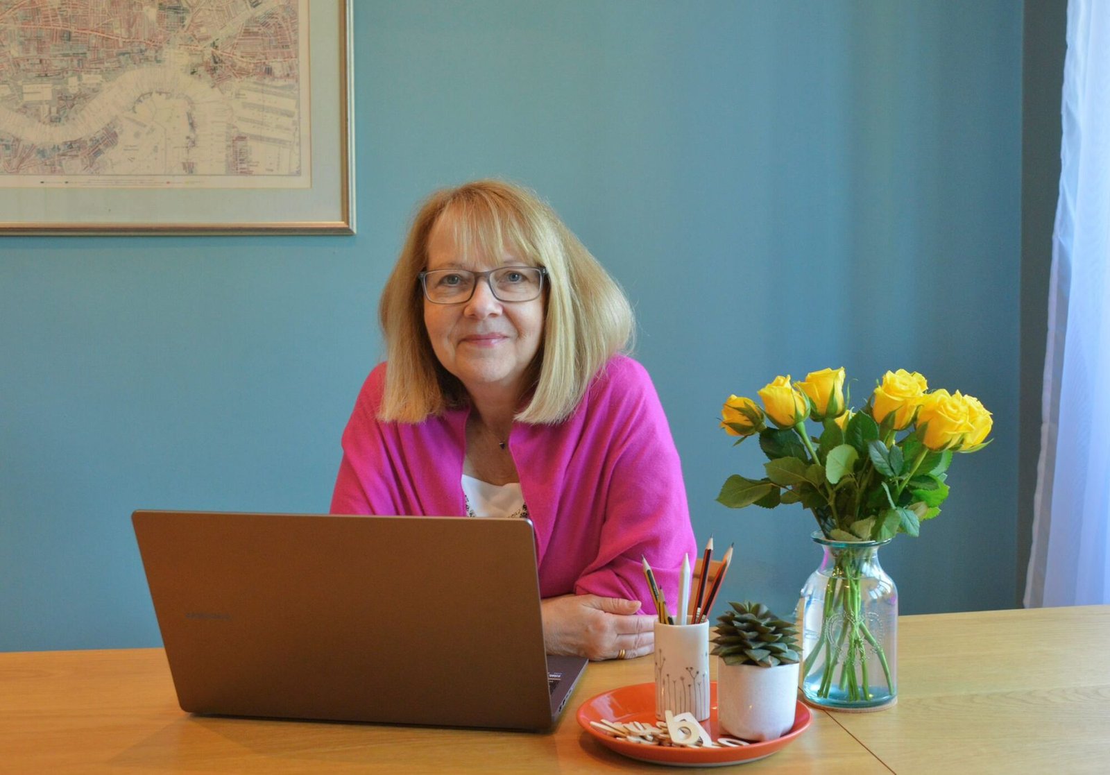 Christine at her desk, in pink, with fresh flowers