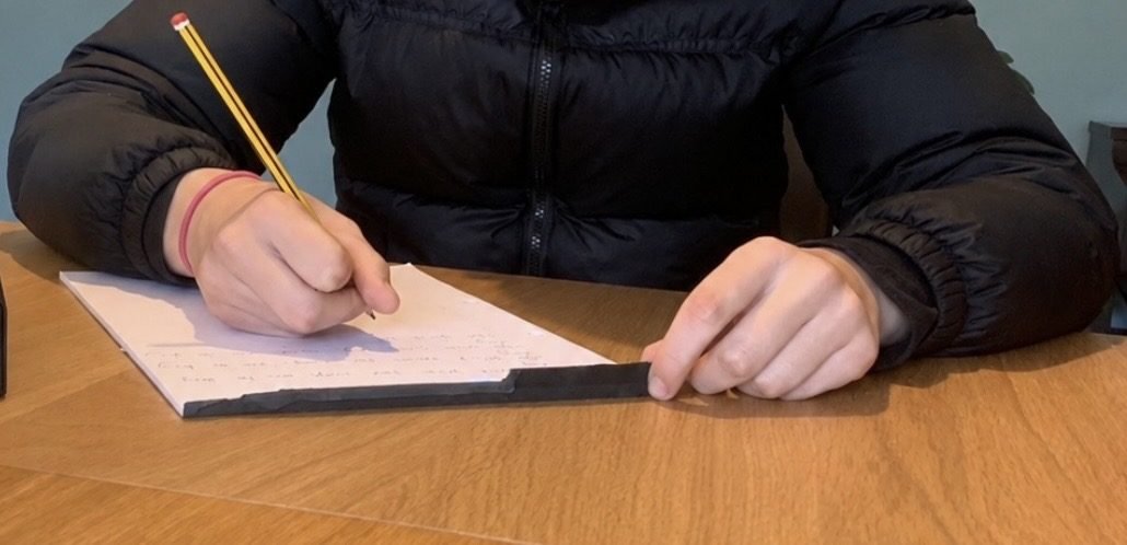 A young person writing at a desk